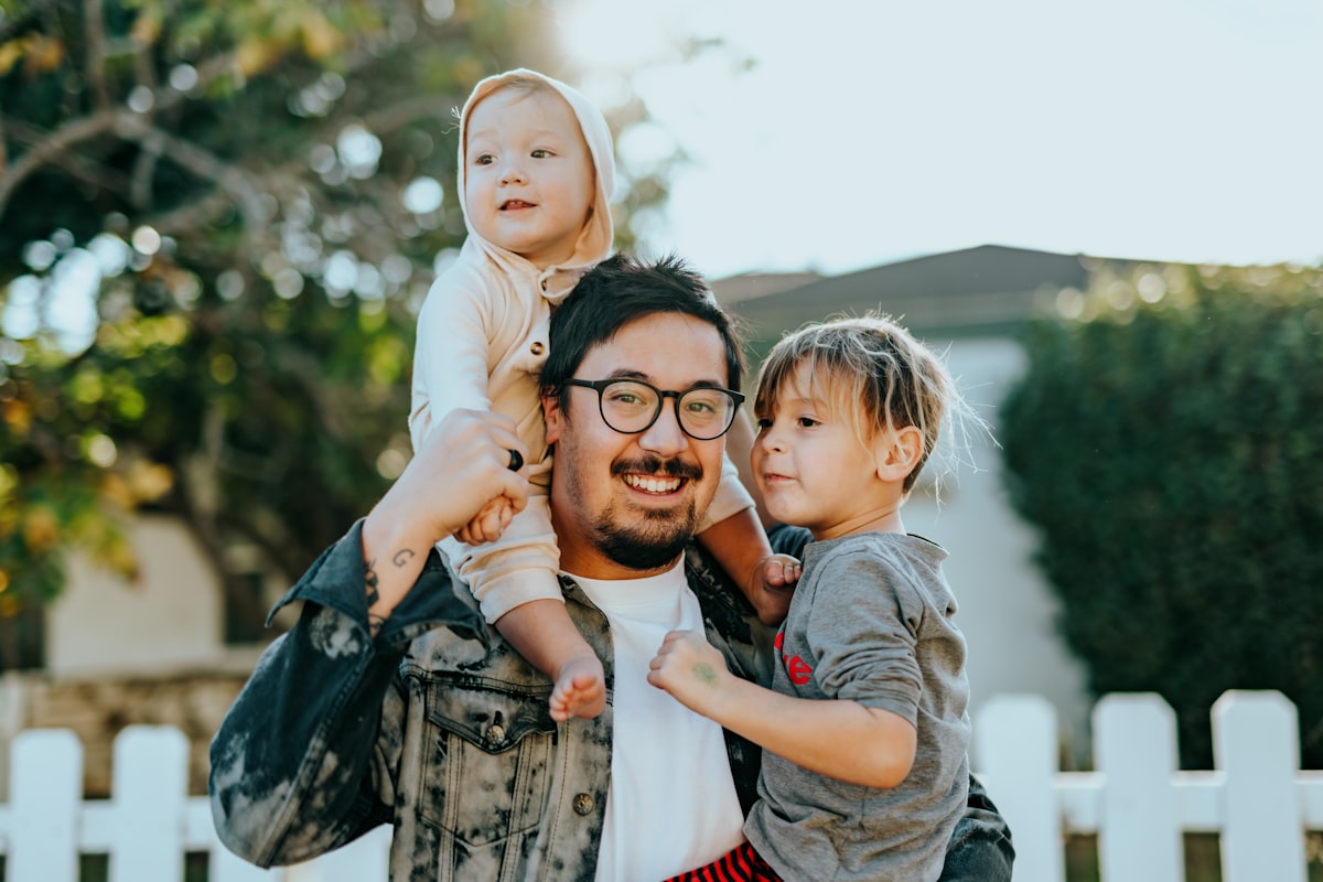 Smiling parent with children outdoors near a suburban home